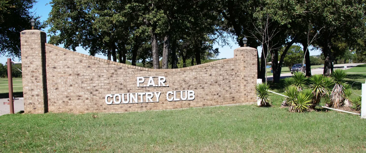 Stone wall with 'Fair Grounds' sign surrounded by greenery.